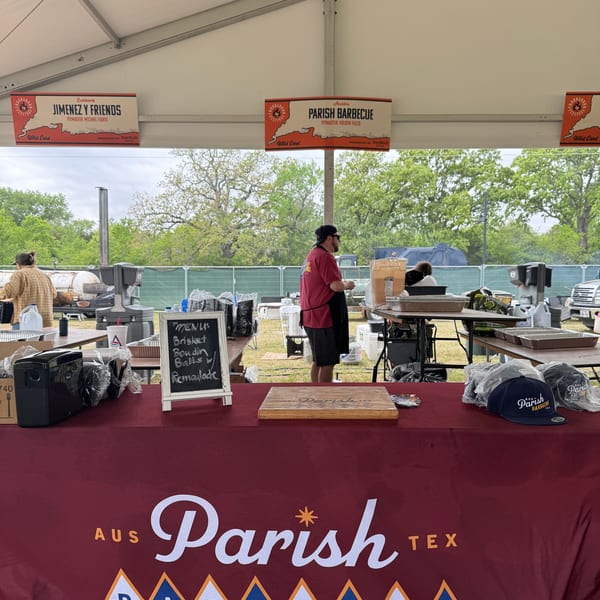 A Parish Barbecue tent with a menu board, merchandise, and a person working behind the counter.